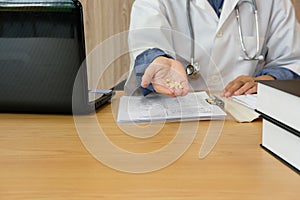 doctor physician pharmacist wearing medical gown coat with stethoscope holding tablets pills