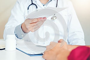 Doctor or physician writing diagnosis and giving a medical prescription to female Patient