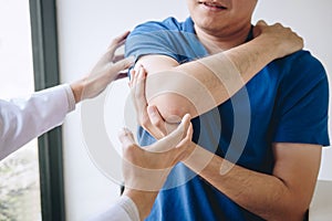 Doctor physiotherapist assisting a male patient while giving exercising treatment massaging the arm of patient in a physio room,