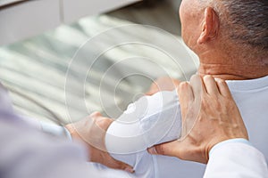 Doctor physiotherapist doing healing treatment to old man. Shoulder pain patient, medical doctor, treatment, massage therapist.