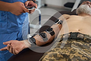 Doctor physiotherapist performs a physiotherapeutic procedure on a military man
