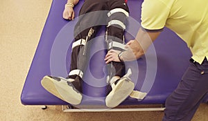 Doctor physiotherapist putting the orthosis for disabled man
