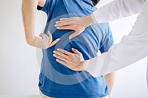 Doctor physiotherapist treating lower back pain patient after while giving exercising treatment on stretching in the clinic,