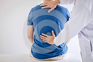 Doctor physiotherapist treating lower back pain patient after while giving exercising treatment on stretching in the clinic,
