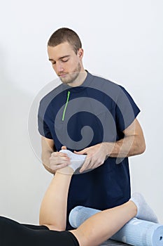 Doctor or Physiotherapist working examining treating injured leg of athlete male patient, Doing the Rehabilitation