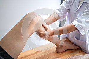 Doctor or Physiotherapist working examining treating injured leg of athlete male patient, Doing the Rehabilitation therapy pain in