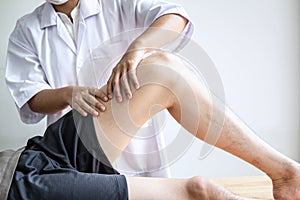 Doctor or Physiotherapist working examining treating injured leg of athlete male patient, Doing the Rehabilitation therapy pain in
