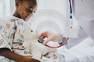 Doctor playfully checking the heart beat of a teddy bear