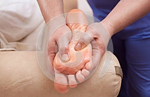The doctor-podiatrist does an examination and massage of the patient`s foot