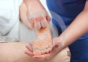 The doctor-podiatrist does an examination and massage of the patient`s foot