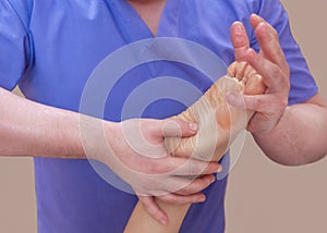 The doctor-podiatrist does an examination and massage of the patient`s foot