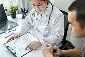 Doctor is pointing on document to explaining disease and illness symptoms for patient before writing