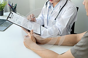 Doctor is pointing on document to explaining disease and symptoms for patient during to talking