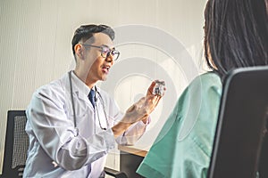 Doctor is pointing to drug bottle and introducing the properties of the painkiller to patient at hospital, healthcare and medical