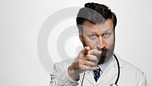 Doctor points his finger to you. Serious man doctor on white background looking at camera and points his finger in