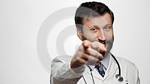 Doctor points his finger to you. Smiling kind man doctor on white background looking at camera and points his finger in