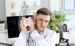 Doctor posing with piggy bank