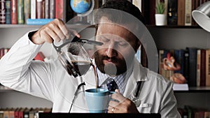 Doctor pours coffee. Slightly tired or sleepy male doctor at his workplace in office works at computer, interrupts to