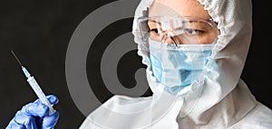Doctor in PPE suit holds syringe for COVID-19 vaccine injection