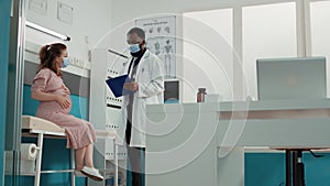 Doctor and pregnant woman with face mask attending checkup visit