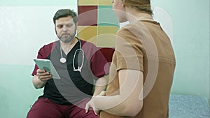 Doctor and pregnant woman look at digital tablet together