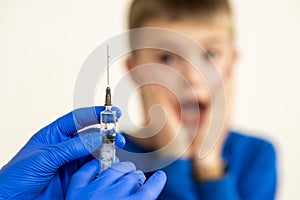Doctor preparing vaccination injection with a syringe to an afraid child boy. Vaccination of children at school concept
