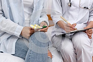 Doctor prescribing pills to patient on clipboard close up