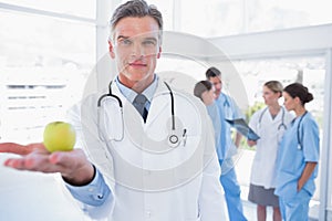 Doctor presenting an apple in his hand