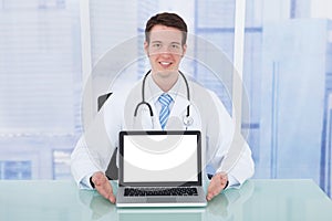 Doctor Presenting Laptop With Blank Screen At Desk