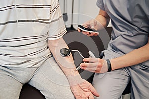Doctor pressing manual muscle testing device to patient arm