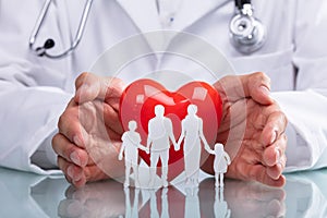 Doctor Protecting Red Heart With Family Figure photo