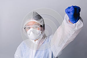 The doctor, in protective gear, raised hand showing his fist. Confident doctor during the fight against coronavirus.