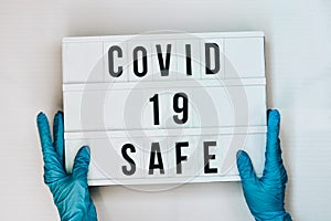 Doctor in protective gloves holding Lightbox with text COVID 19 SAFE. Back to school. Social distancing. School quarantine concept