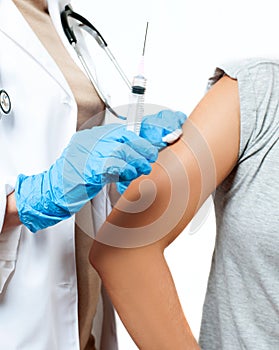 Doctor in protective gloves is injecting coronavirus vaccine to patient`s arm for prevention, immunization and treatment from