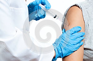 Doctor in protective gloves is injecting coronavirus vaccine to patient`s arm for prevention, immunization and treatment from