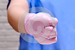 Doctor in protective gloves shows a vulgar gesture of a fig sign, closeup