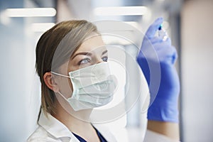 Doctor in protective mask with an ampule in hand