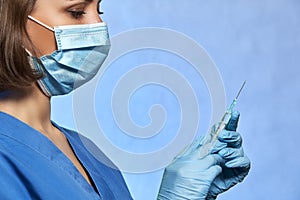 Doctor in protective mask and blue latex gloves with syringe with a medicine vaccine from Coronavirus