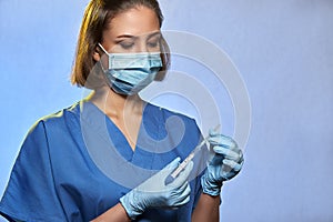 Doctor in protective mask and blue latex gloves with syringe with a medicine vaccine from Coronavirus