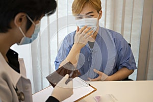 Doctor in protective mask explaining treatment plan to patient.