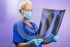 A doctor in protective mask, gloves and stethoscope holding an x-ray picture