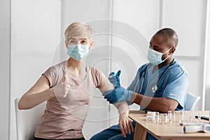 Doctor in protective mask inject vaccine to stimulate immunity of woman patient at risk of coronavirus photo