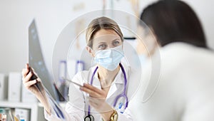 Doctor in protective mask showing patient X ray