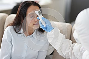 Doctor in protective suit measures temperature with noncontact infrared thermometer photo