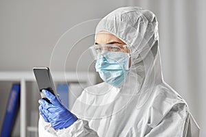 Doctor in protective wear with smartphone