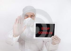 A doctor in the protective workwear display the digital tablet with message COVID-19