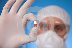 A doctor in the protective workwear display the pill