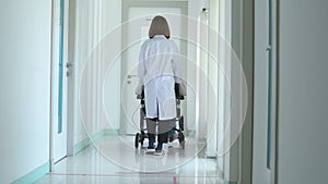 Doctor pushing and assisting patient along corridor in the hospital