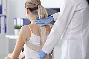 Doctor puts back brace on patient closeup