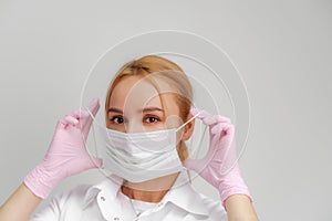 The doctor puts on a mask. Close-up portrait of medical staff. A woman in a protective mask .Isolated on a white